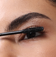 Eine Nahaufnahme einer Person, die mit einem Zauberstab die schwarze Nanolash-Mascara auf ihre oberen Wimpern aufträgt.