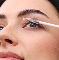 Eine Frau trägt mit einem Pinsel Mascara auf und betont so sorgfältig ihre Wimpern, um ein glänzendes und edles Aussehen zu erzielen.